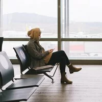 Reisende Frau wartet am Flughafen auf einen verspäteten Anschlussflug.