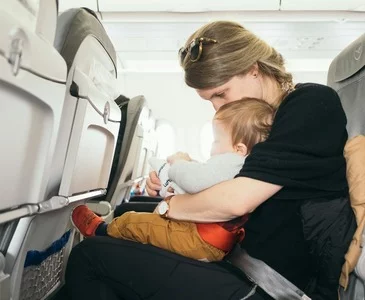 Baby auf dem Schoß einer Frau im Flugzeug