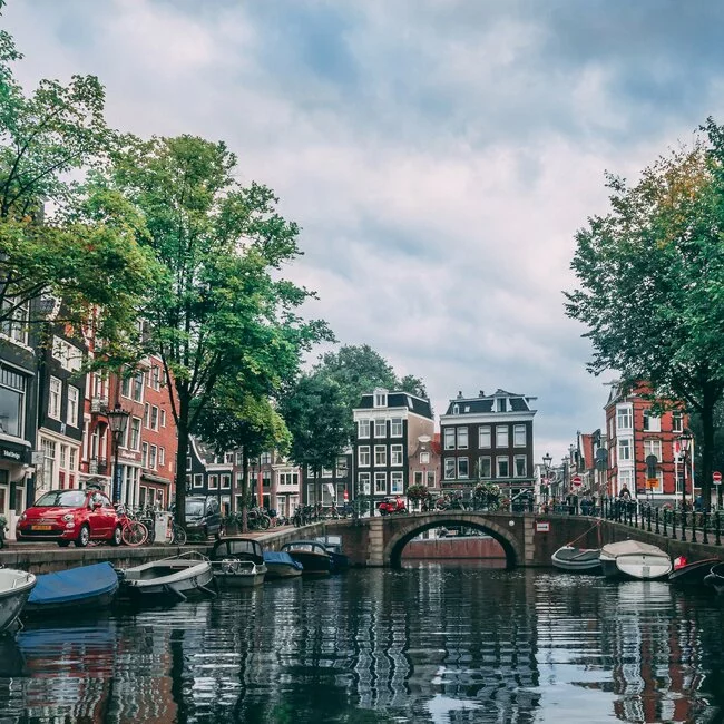 Ein Kanal in Amsterdam mit Booten und Gebäuden entlang.