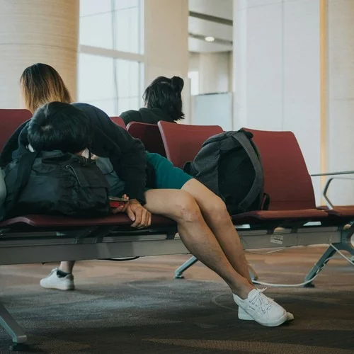Person schläft am Flughafen wegen der Zeitverschiebung und einem schlimmen Jetlag